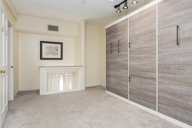 interior space featuring rail lighting, carpet, visible vents, and baseboards