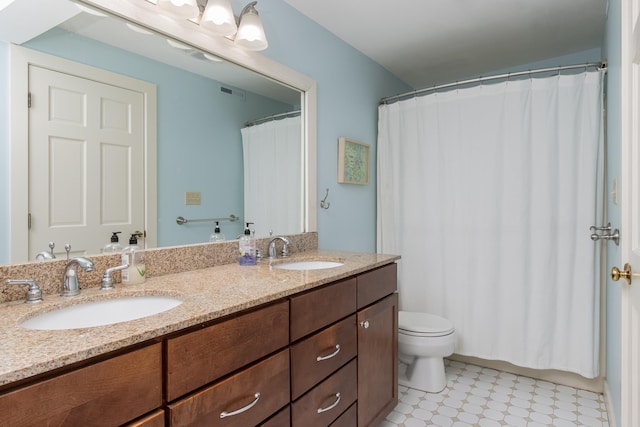 bathroom with double vanity, visible vents, toilet, and a sink