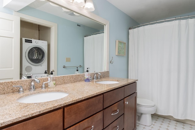 bathroom with toilet, a sink, visible vents, and stacked washer / drying machine