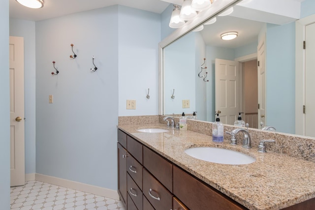 bathroom featuring double vanity, baseboards, a sink, and tile patterned floors