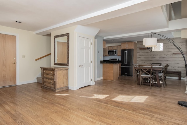 kitchen with dark countertops, stainless steel microwave, light wood-style floors, high end black fridge, and baseboards