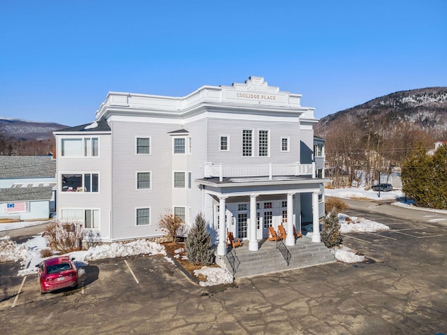 back of property featuring covered porch, a mountain view, and a balcony