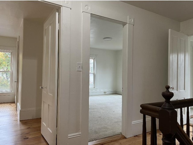 hall featuring light wood-type flooring and baseboards