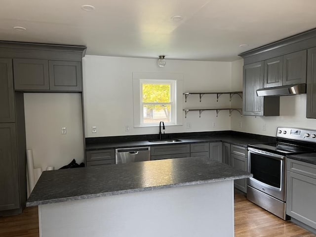 kitchen with stainless steel appliances, a sink, under cabinet range hood, and gray cabinetry