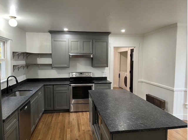 kitchen featuring radiator, independent washer and dryer, stainless steel appliances, open shelves, and a sink