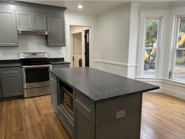 kitchen with a kitchen island, wood finished floors, stainless steel appliances, crown molding, and under cabinet range hood