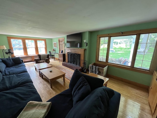 living room featuring light wood-style floors and a fireplace with raised hearth