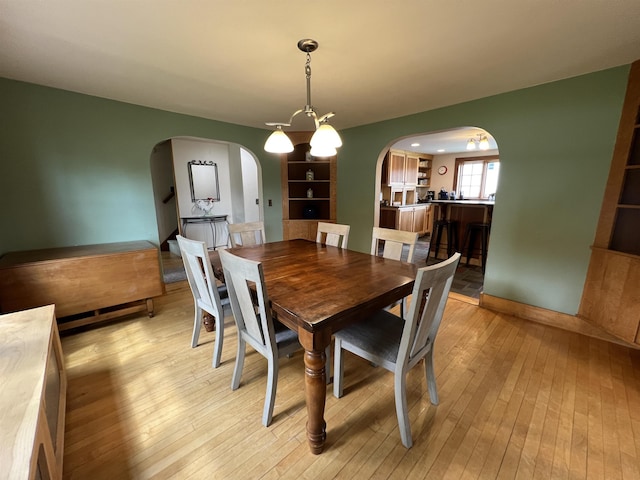 dining room featuring light wood-style floors and arched walkways