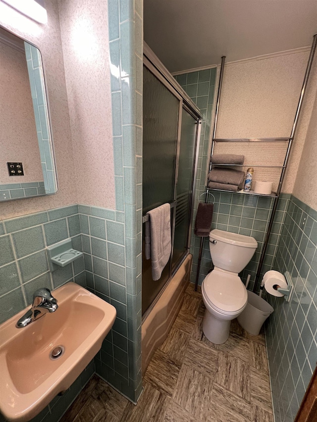 full bath featuring a wainscoted wall, a sink, tile walls, and toilet