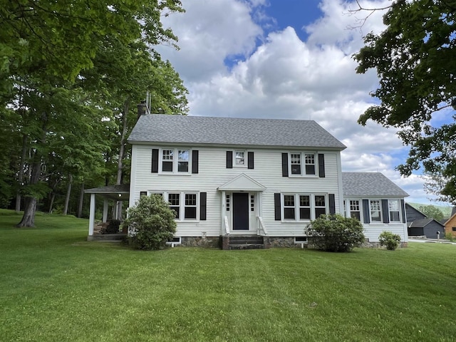 colonial inspired home featuring a front yard and roof with shingles