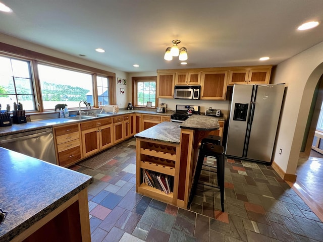 kitchen featuring arched walkways, appliances with stainless steel finishes, stone tile flooring, and recessed lighting