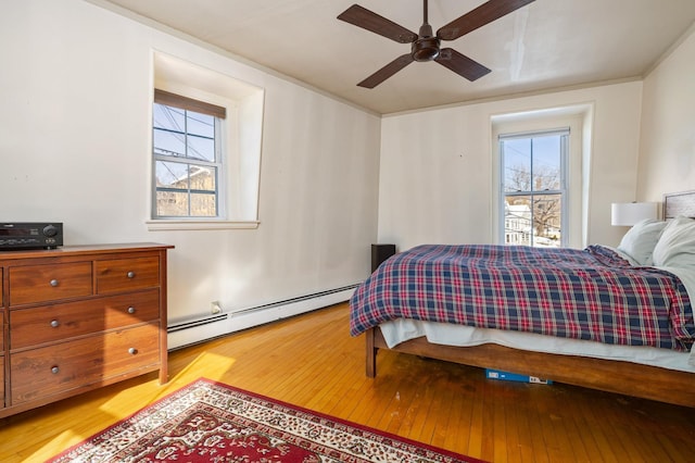 bedroom with light wood-style floors, ceiling fan, and baseboard heating