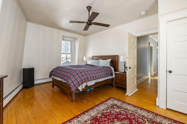 bedroom featuring light wood-type flooring, a baseboard radiator, crown molding, and a ceiling fan