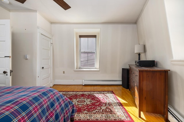 bedroom with a baseboard heating unit, light wood-style flooring, baseboard heating, and a ceiling fan