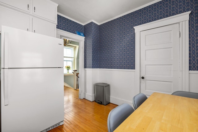 office with a wainscoted wall, light wood-style flooring, ornamental molding, baseboards, and wallpapered walls