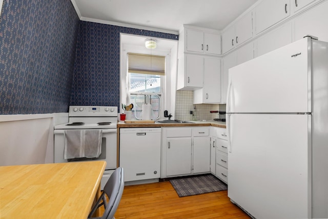 kitchen with white appliances, a sink, white cabinetry, and wallpapered walls