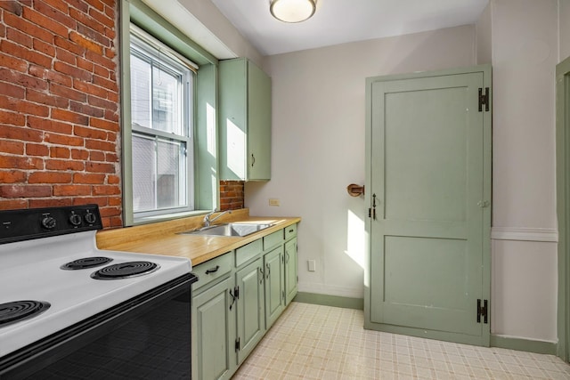 kitchen featuring green cabinets, light countertops, range with electric cooktop, and a sink