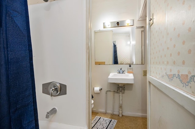 bathroom with tile patterned flooring, toilet, a sink, baseboards, and shower / bathtub combination with curtain