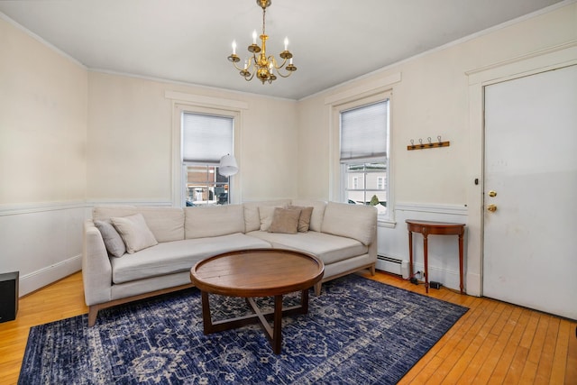 living room featuring hardwood / wood-style flooring, a chandelier, baseboard heating, and ornamental molding