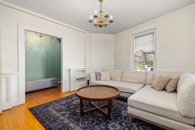 living area featuring hardwood / wood-style flooring, a wainscoted wall, an inviting chandelier, crown molding, and a decorative wall