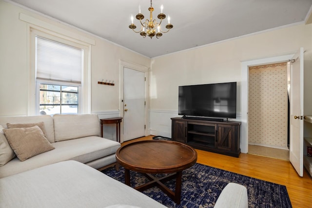 living room featuring a wainscoted wall, a notable chandelier, ornamental molding, and wood finished floors