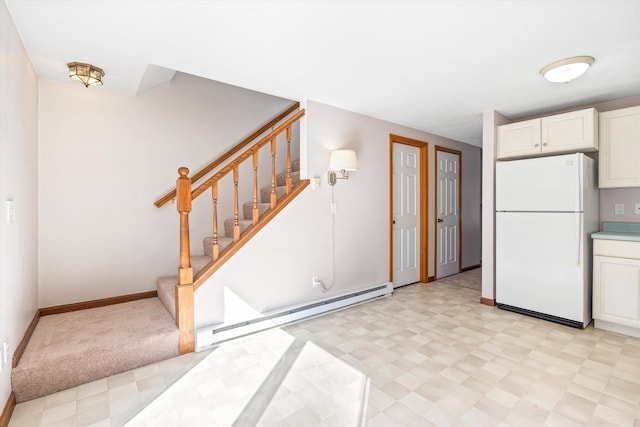 kitchen featuring light floors, a baseboard radiator, freestanding refrigerator, white cabinets, and baseboards