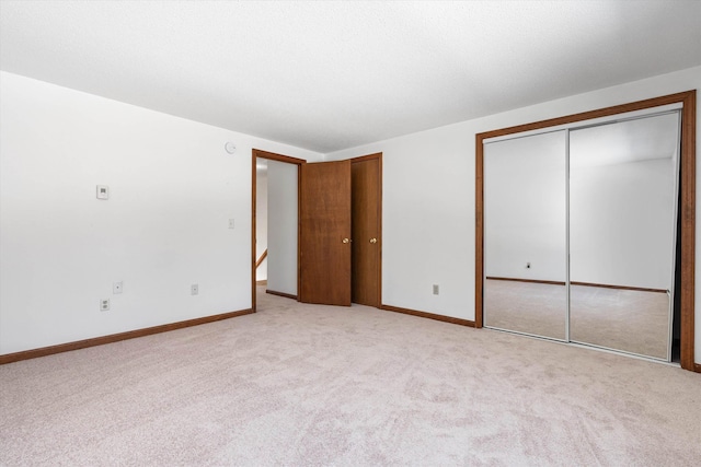 unfurnished bedroom featuring carpet floors, baseboards, and two closets