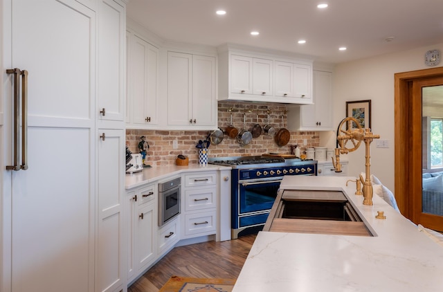 kitchen with tasteful backsplash, white cabinets, wood finished floors, double oven range, and recessed lighting