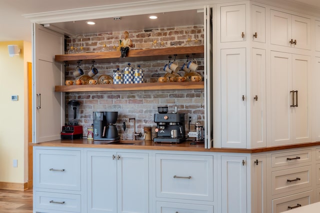 bar featuring light wood-style floors, a dry bar, and baseboards