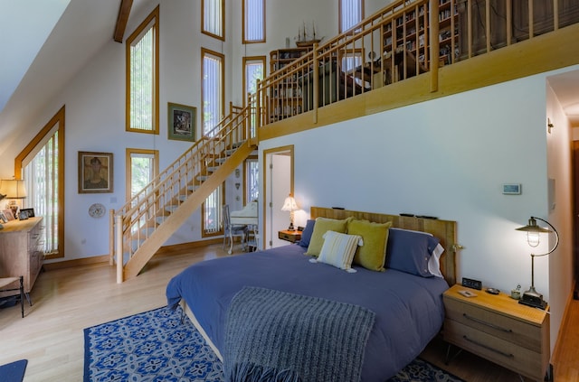 bedroom featuring a towering ceiling, baseboards, and wood finished floors