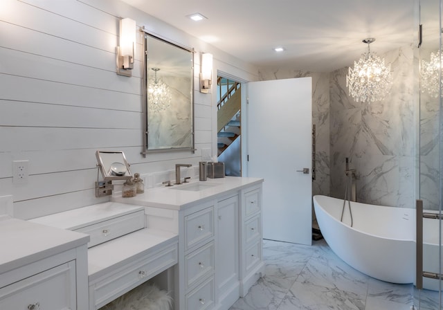 full bath featuring marble finish floor, vanity, a freestanding tub, a notable chandelier, and recessed lighting