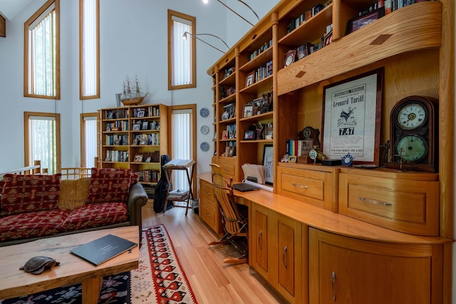 office area with built in desk, a high ceiling, and light wood-style flooring