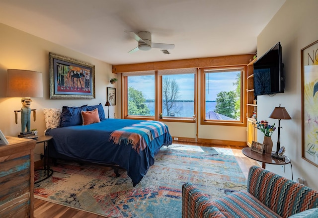 bedroom with ceiling fan, visible vents, and wood finished floors