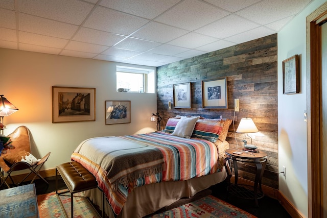 bedroom featuring an accent wall, a drop ceiling, and baseboards