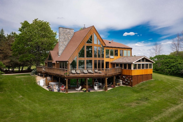 rear view of house with a deck, a patio, a yard, and a chimney