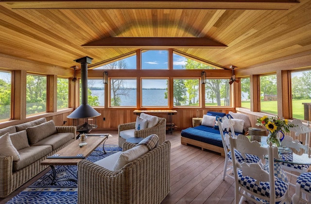 sunroom featuring a water view, vaulted ceiling with beams, wooden ceiling, and a wood stove