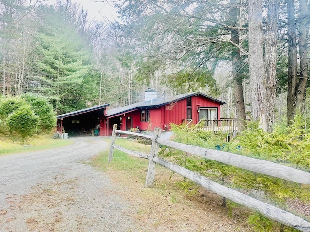 view of front of property with driveway, a chimney, and a wooded view