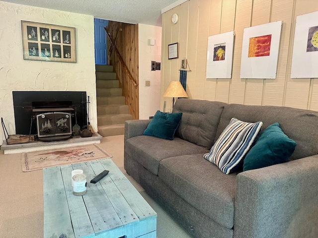 living room featuring a glass covered fireplace, stairway, and a textured ceiling