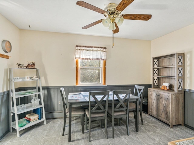 dining area with a ceiling fan, wainscoting, and tile patterned floors