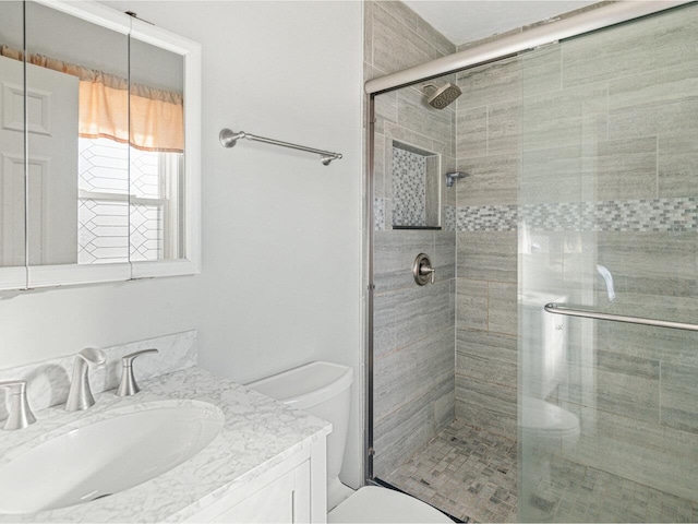 bathroom with a stall shower, vanity, and toilet