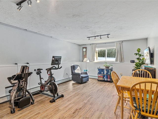 workout room with a textured ceiling, a baseboard heating unit, baseboard heating, and wood finished floors