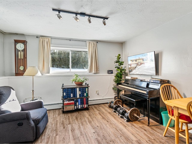 living area with a textured ceiling, a baseboard radiator, and wood finished floors