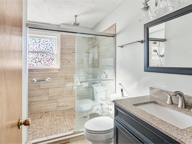 full bath featuring vanity, a shower stall, toilet, and a textured ceiling