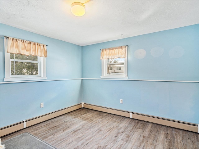 spare room featuring a textured ceiling, baseboard heating, and wood finished floors