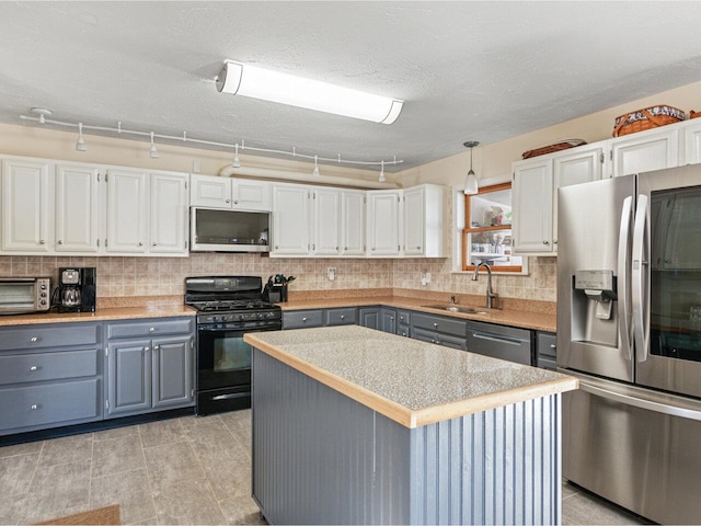 kitchen with stainless steel appliances, gray cabinets, a sink, and tasteful backsplash