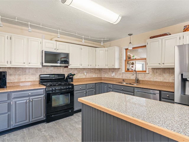 kitchen with a sink, stainless steel appliances, gray cabinetry, white cabinetry, and backsplash