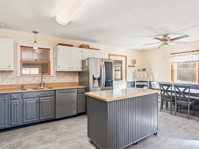 kitchen with gray cabinetry, a sink, white cabinetry, light countertops, and appliances with stainless steel finishes