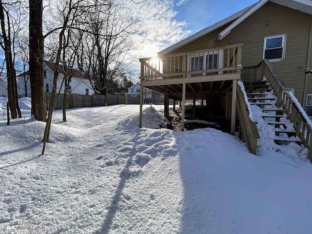 snow covered property featuring stairs, a deck, and fence