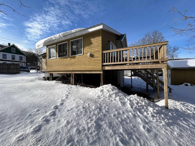 snow covered house with a wooden deck and stairs