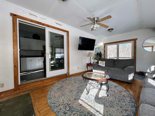 living room with lofted ceiling, wood finished floors, a ceiling fan, and baseboards